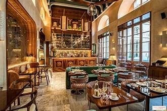 Luxurious interior with wooden furnishings, green upholstered seating, fireplace, and large windows overlooking a city view