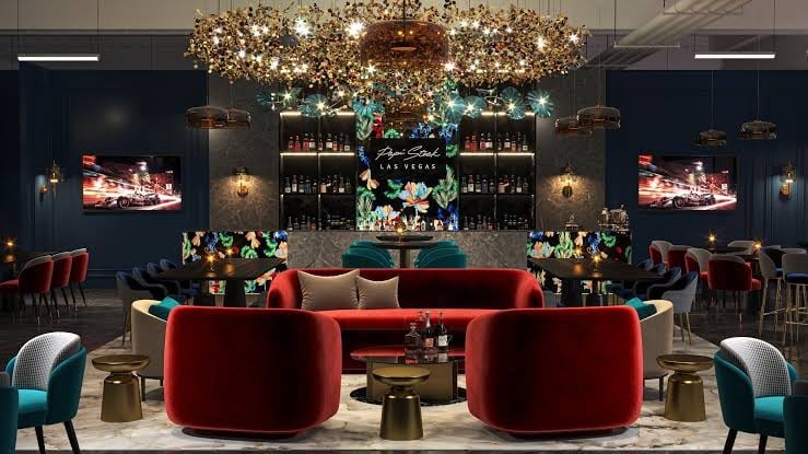 Luxury lounge with red curved seating, gold chandelier, teal accents, and dark walls with bar shelving