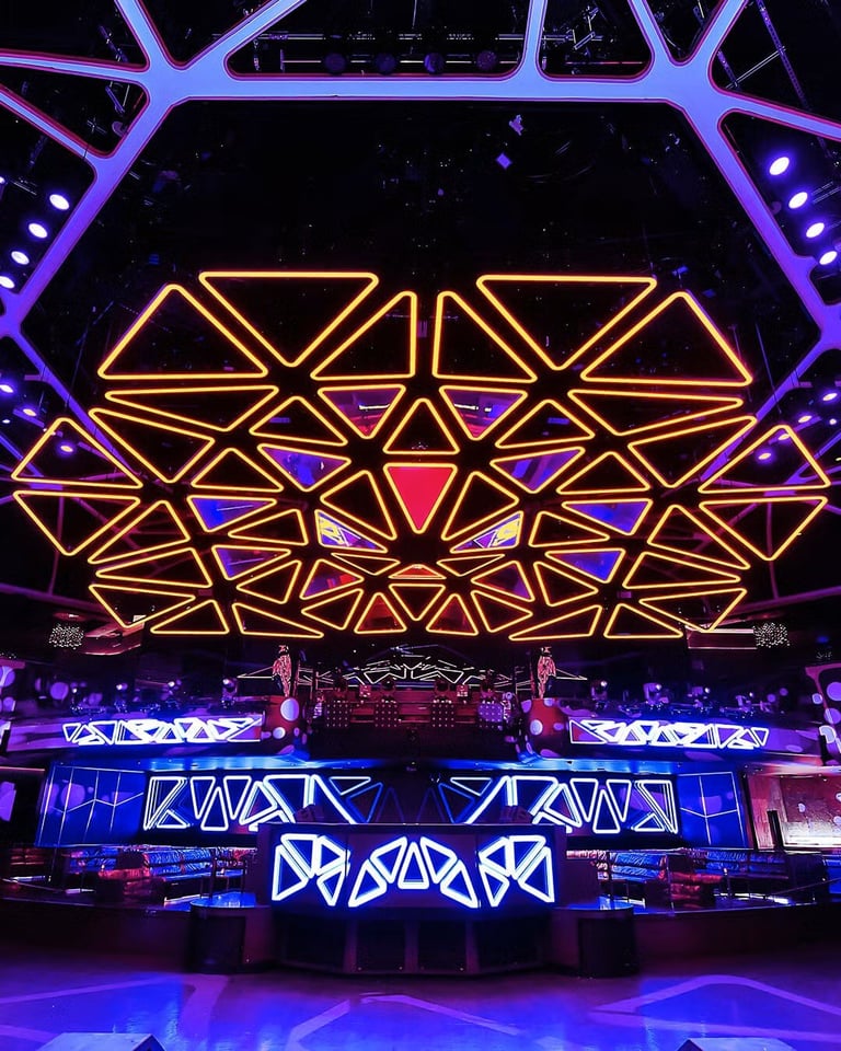Stage with large geometric neon light display in orange and blue, featuring triangular patterns and purple ambient lighting