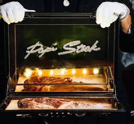 Open display case with steaks lit by warm lights, held by gloved hands, with Rye Steak text on black background