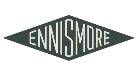 Ennismore brand logo, dark green diamond-shaped emblem with white serif lettering