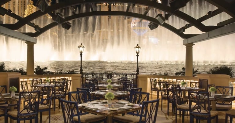 Upscale rooftop dining area with wooden chairs, tables, and panoramic city views under a pergola structure