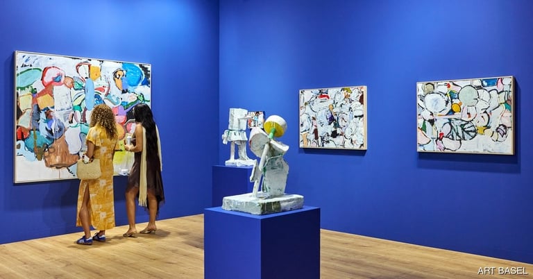 Gallery visitors viewing colorful abstract artworks displayed on blue walls and a blue pedestal with sculpture