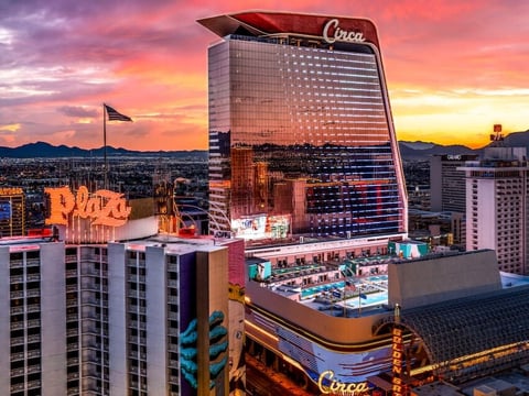 Circa hotel casino in Las Vegas at sunset with pink and orange sky, surrounded by other downtown buildings