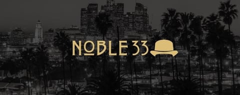 Noble33 logo with yellow fedora hat over black and white cityscape with palm trees