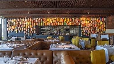 Upscale restaurant interior with leather seating, amber glass wall installation, and tables set for dining