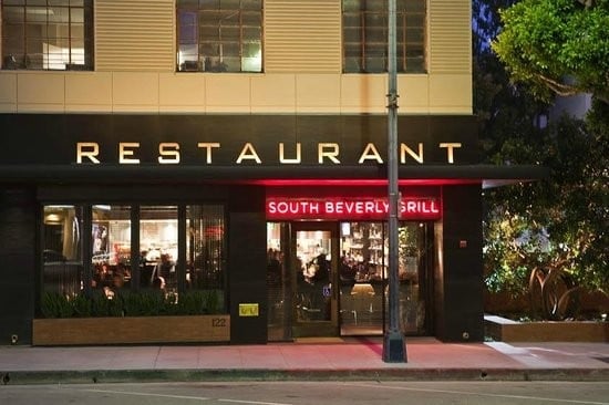 South Beverly Grill restaurant storefront at night with illuminated signage on a dark facade, street level entrance with windows