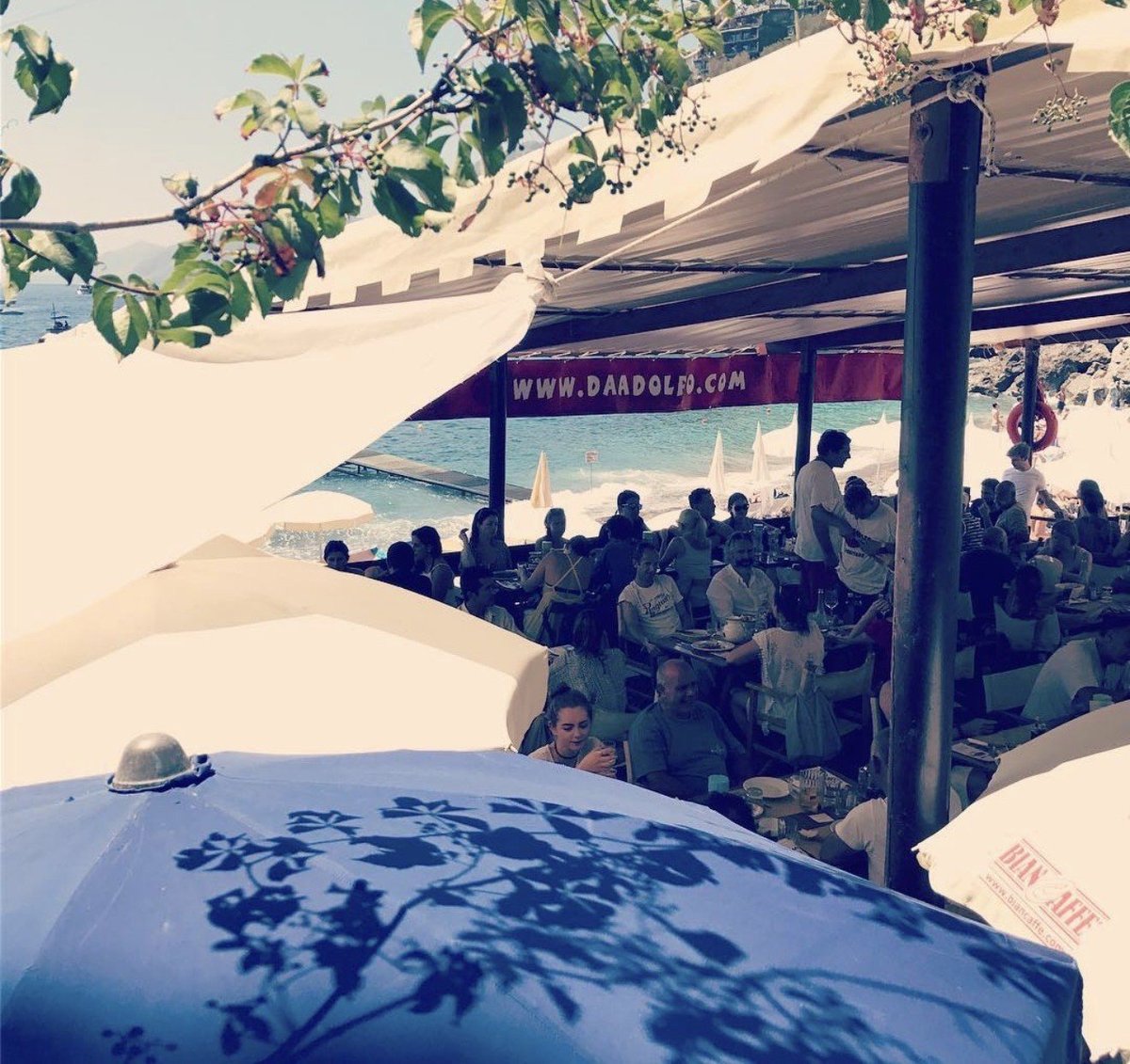 Da Adolfo beach restaurant in Laurito Bay Positano with wooden boats and turquoise water