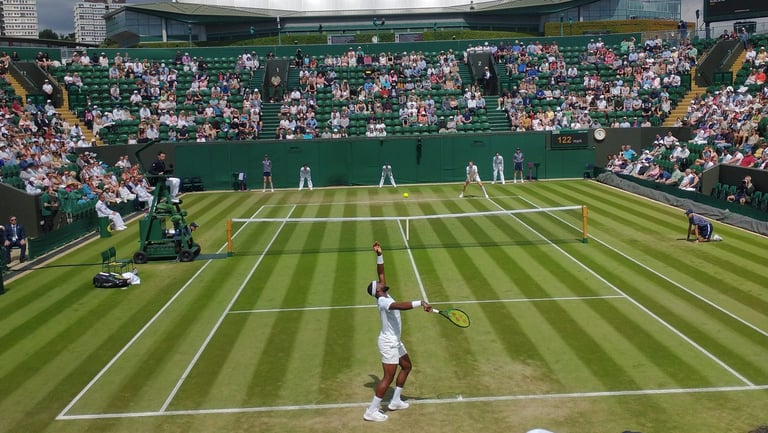 Tennis match on grass court at Wimbledon with players, umpire, and crowd in stadium