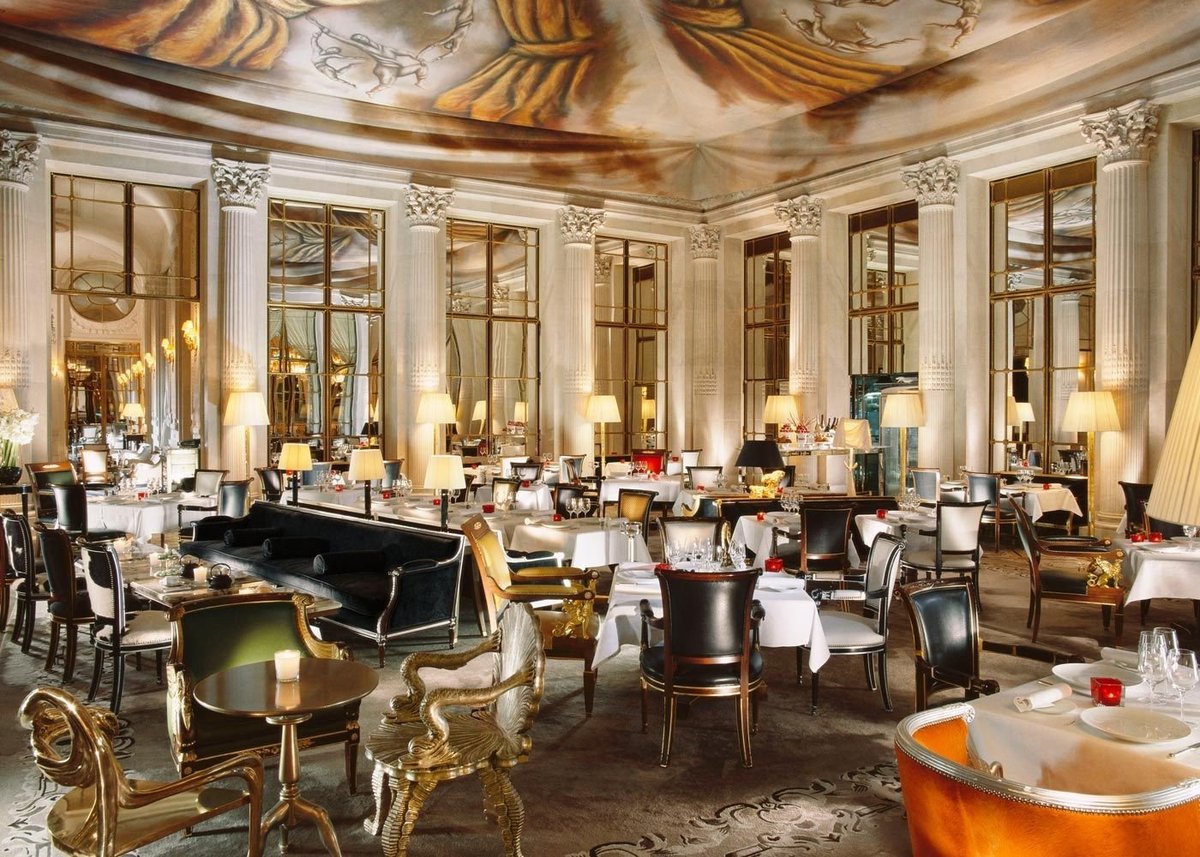 Elegant luxury dining room with ornate ceiling, grand piano, crystal chandeliers, and formal table settings